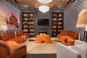 A modern living room with a fireplace, sofas, and a large TV.