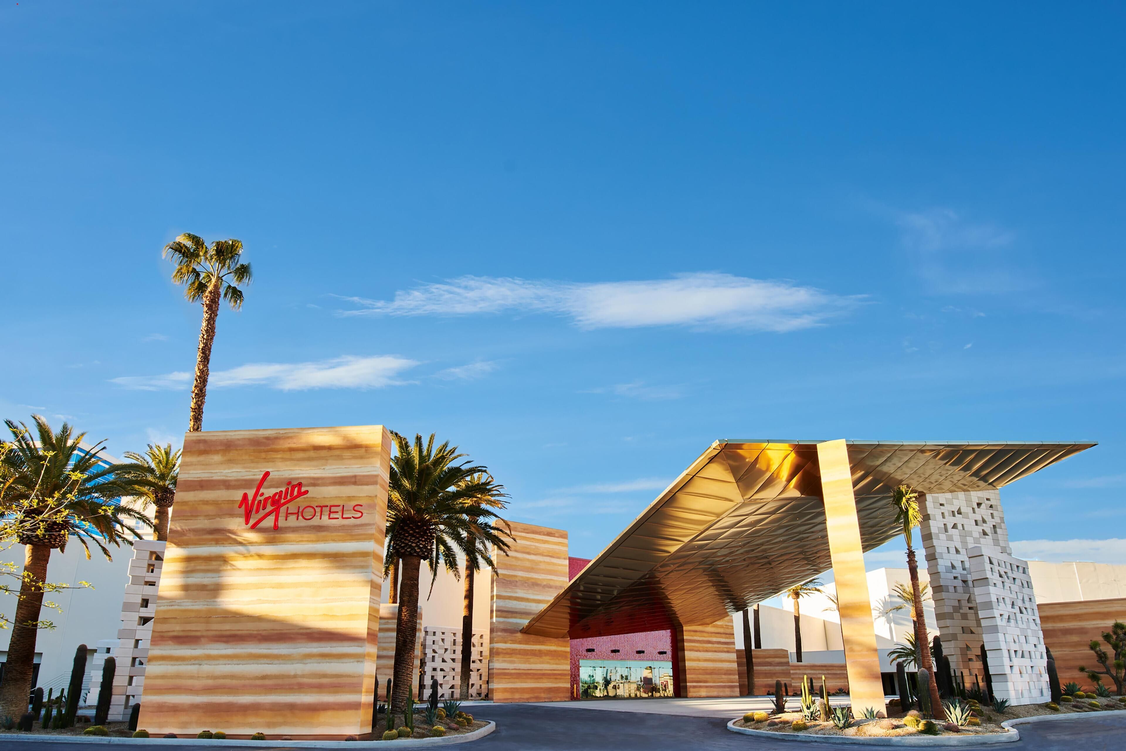 Een modern gebouw met een opvallend Virgin Hotels bord, met een uniek architectonisch ontwerp, een schuin dak en een gegeerd gevelpatroon.
