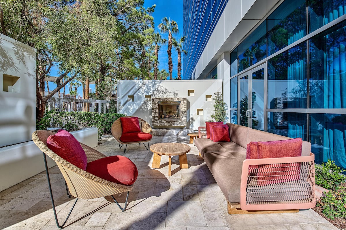 An outdoor seating area with wicker chairs and a sofa, a stone fireplace, and a view of tall buildings.