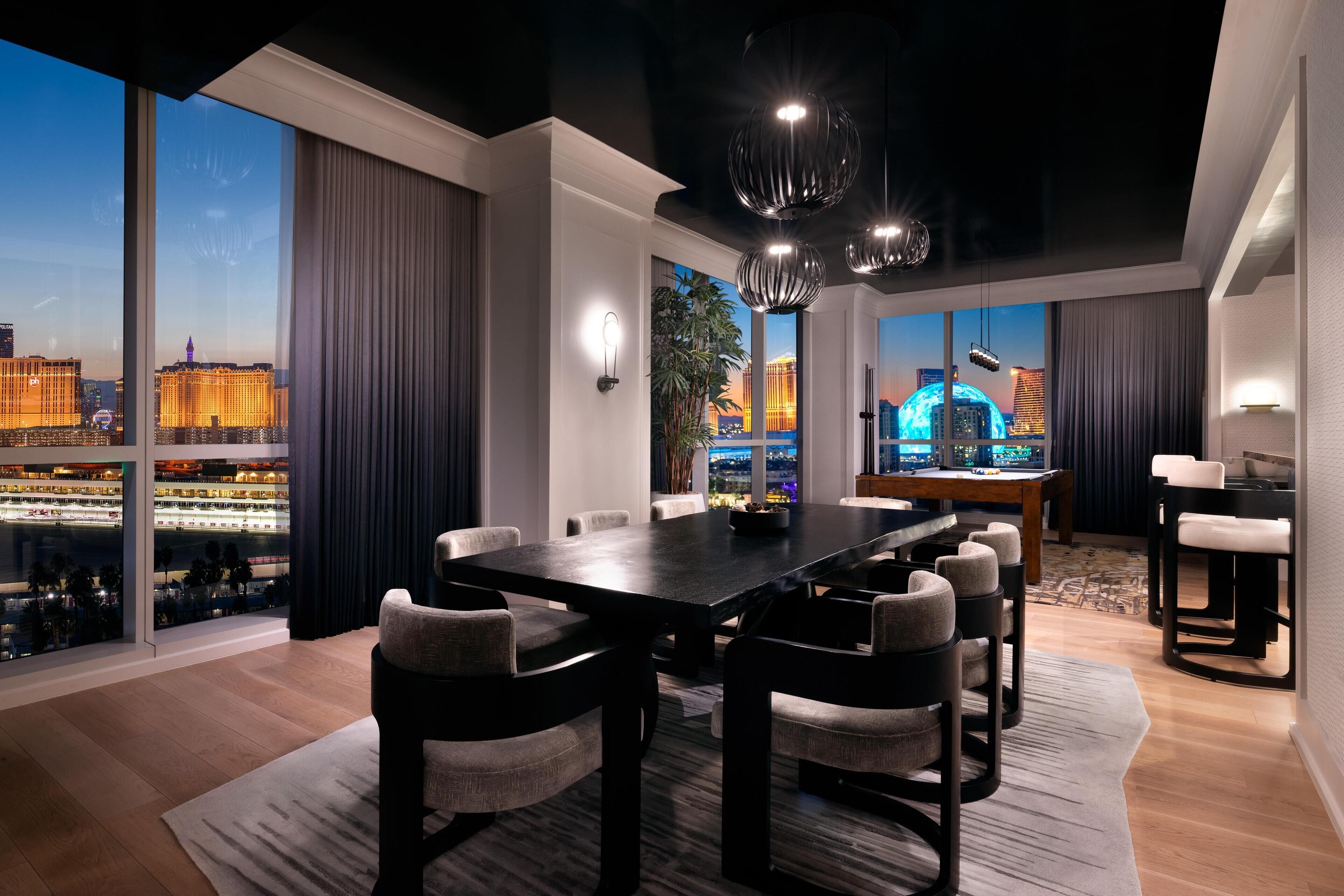 Un espace de restauration moderne, doté d’une grande table et de chaises, de larges fenêtres offrant une vue sur la ville et d’un éclairage contemporain.