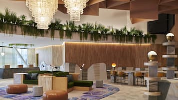 Un vestíbulo moderno con mostrador de recepción de madera, zona de estar con asientos verdes y una lámpara decorativa.