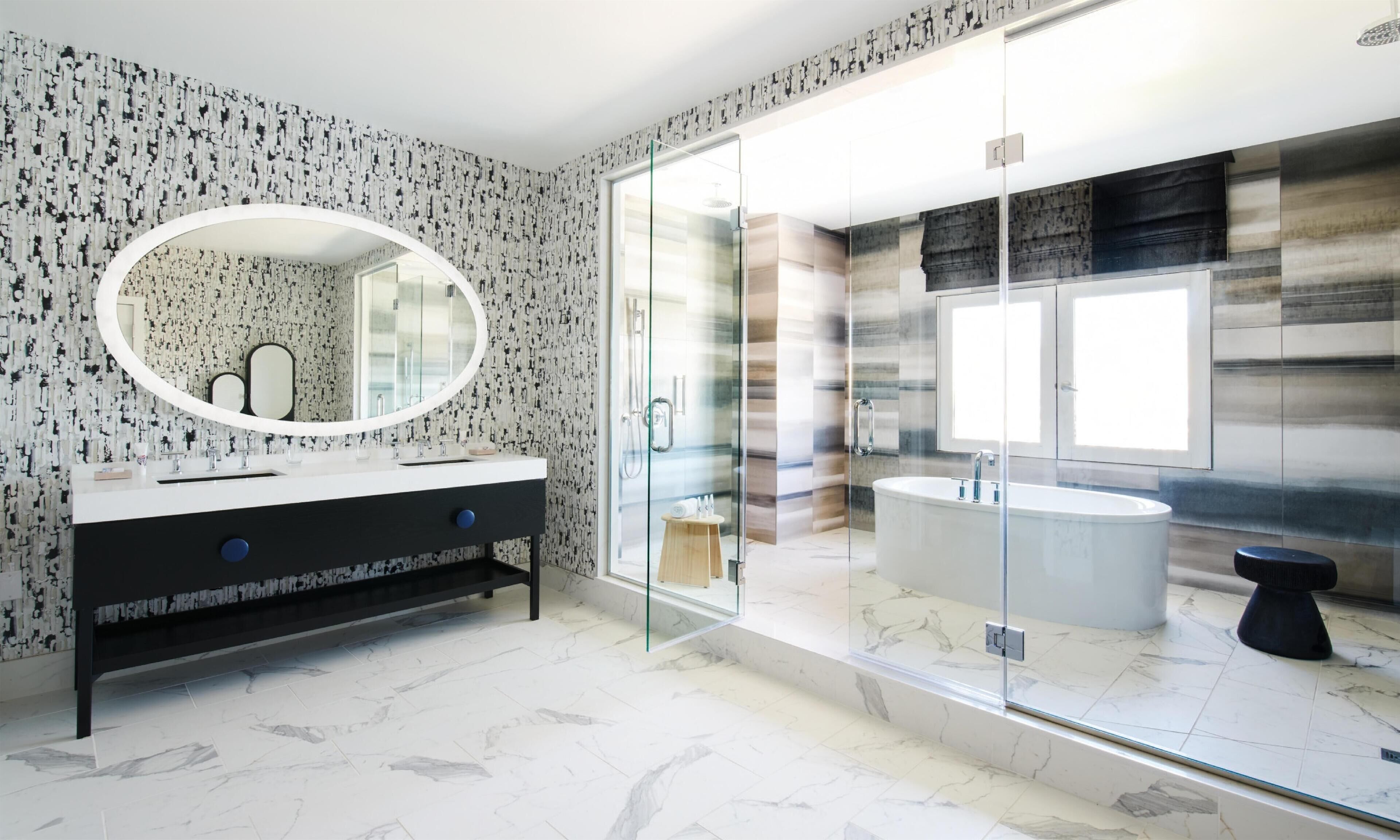 A modern bathroom with a round mirror, a black vanity, a glass-enclosed shower, and a marble-tiled floor.