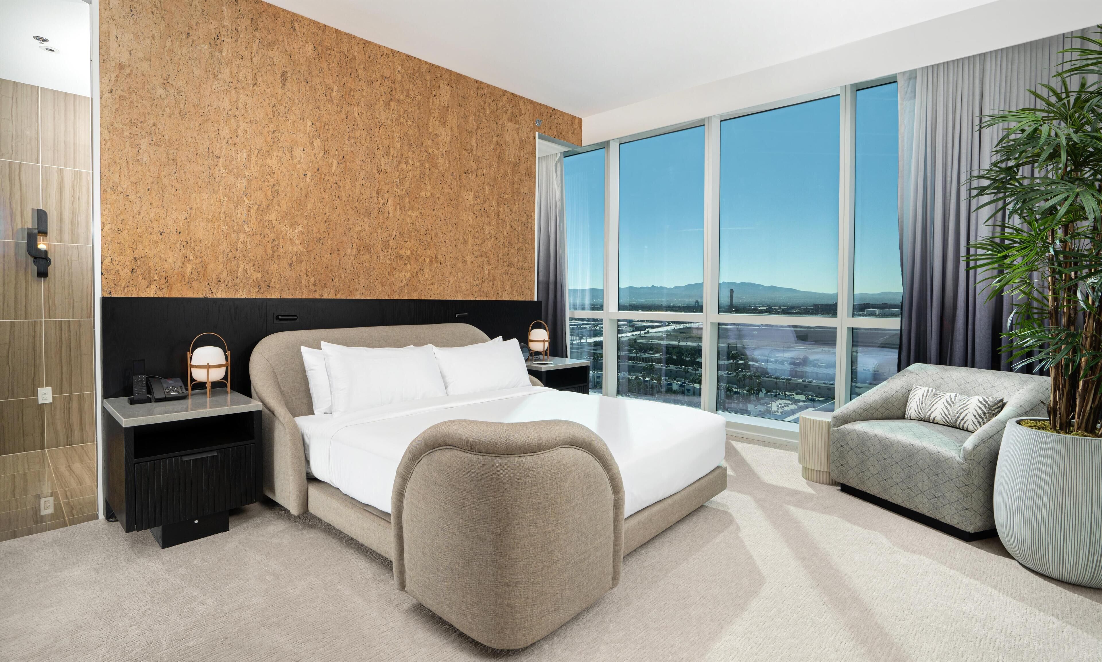 Une chambre d’hôtel moderne dotée d’un grand lit, d’un coin salon et offrant une vue sur le paysage urbain.