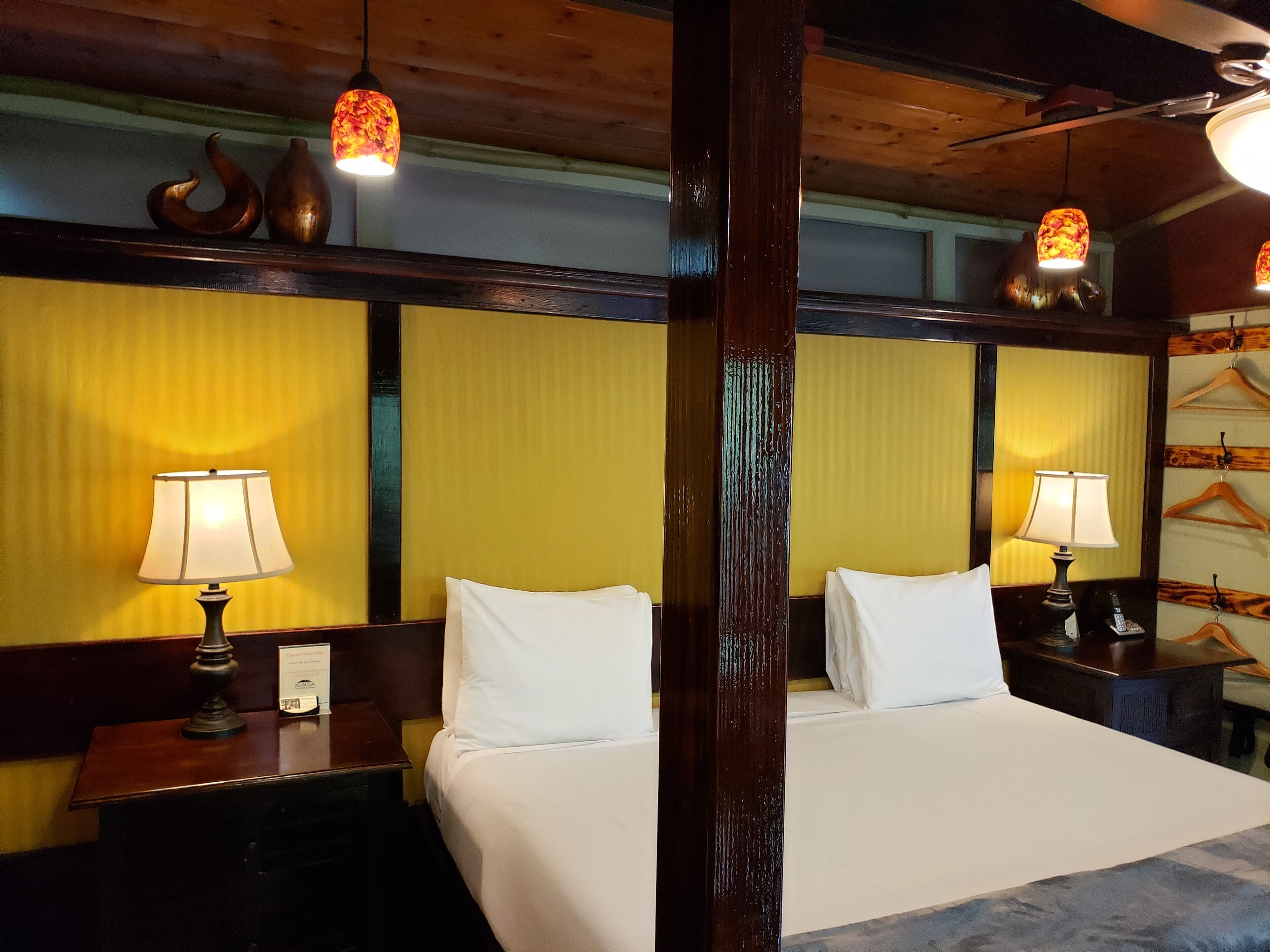 A hotel room with two beds, wooden headboards, and two bedside lamps.