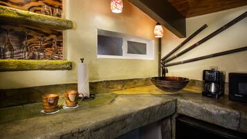 A kitchen with a stone countertop, a window, a coffee maker, and a bowl.