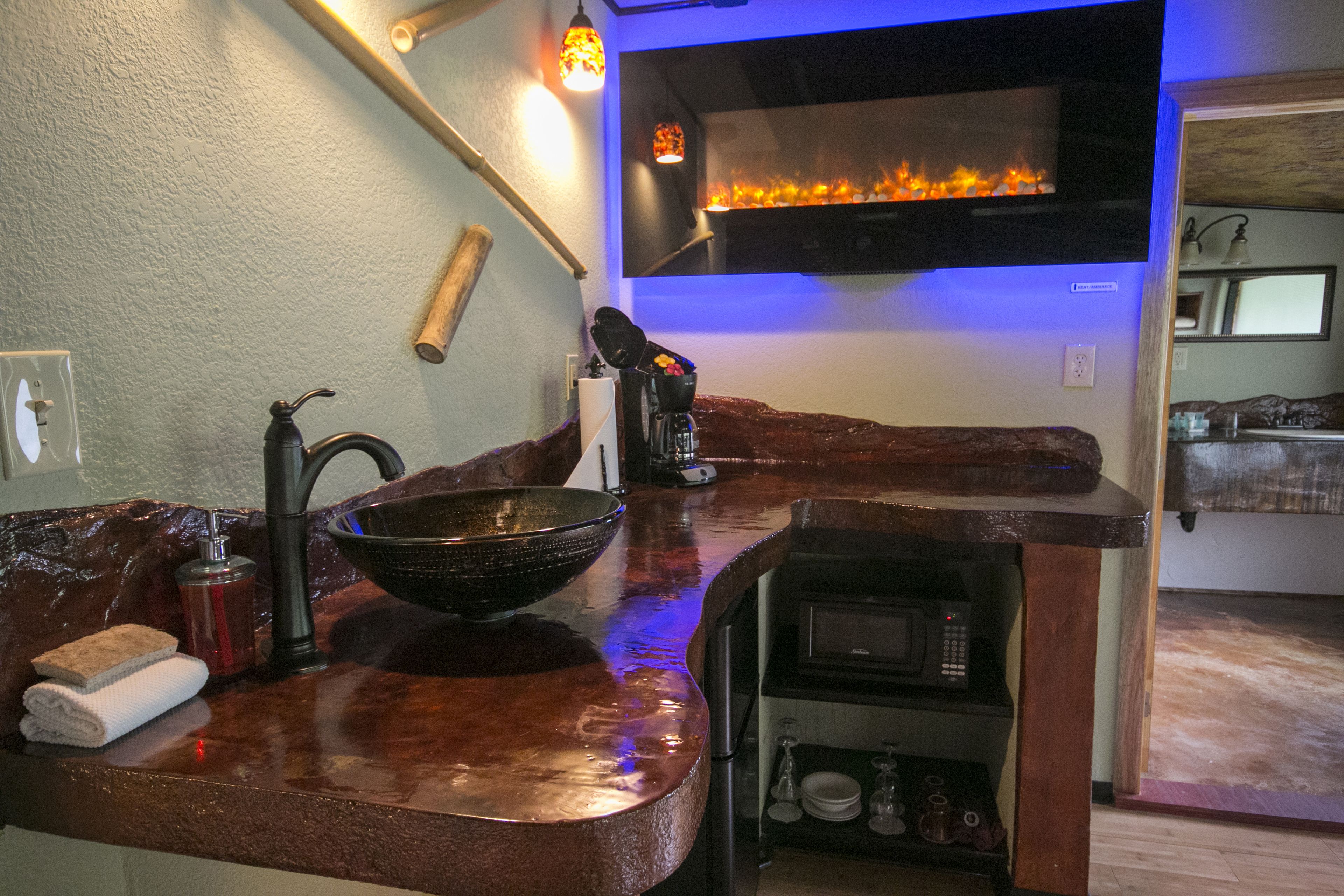 A kitchen with a copper countertop, a large bowl, a faucet, a microwave, and a wall-mounted oven.