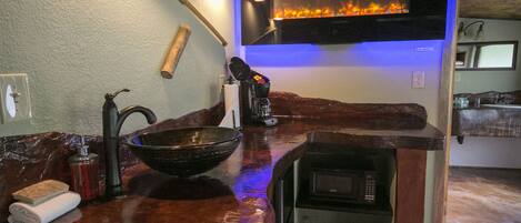 A kitchen with a copper countertop, a large bowl, a faucet, a microwave, and a wall-mounted oven.