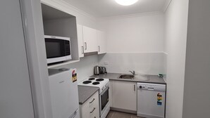 A compact kitchen with a microwave, toaster, kettle, and a built-in oven. - Chasely Apartment Hotel (Auchenflower)