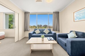 A modern hotel room with a sofa set, a coffee table, and a view of the cityscape. - Chasely Apartment Hotel (Auchenflower)