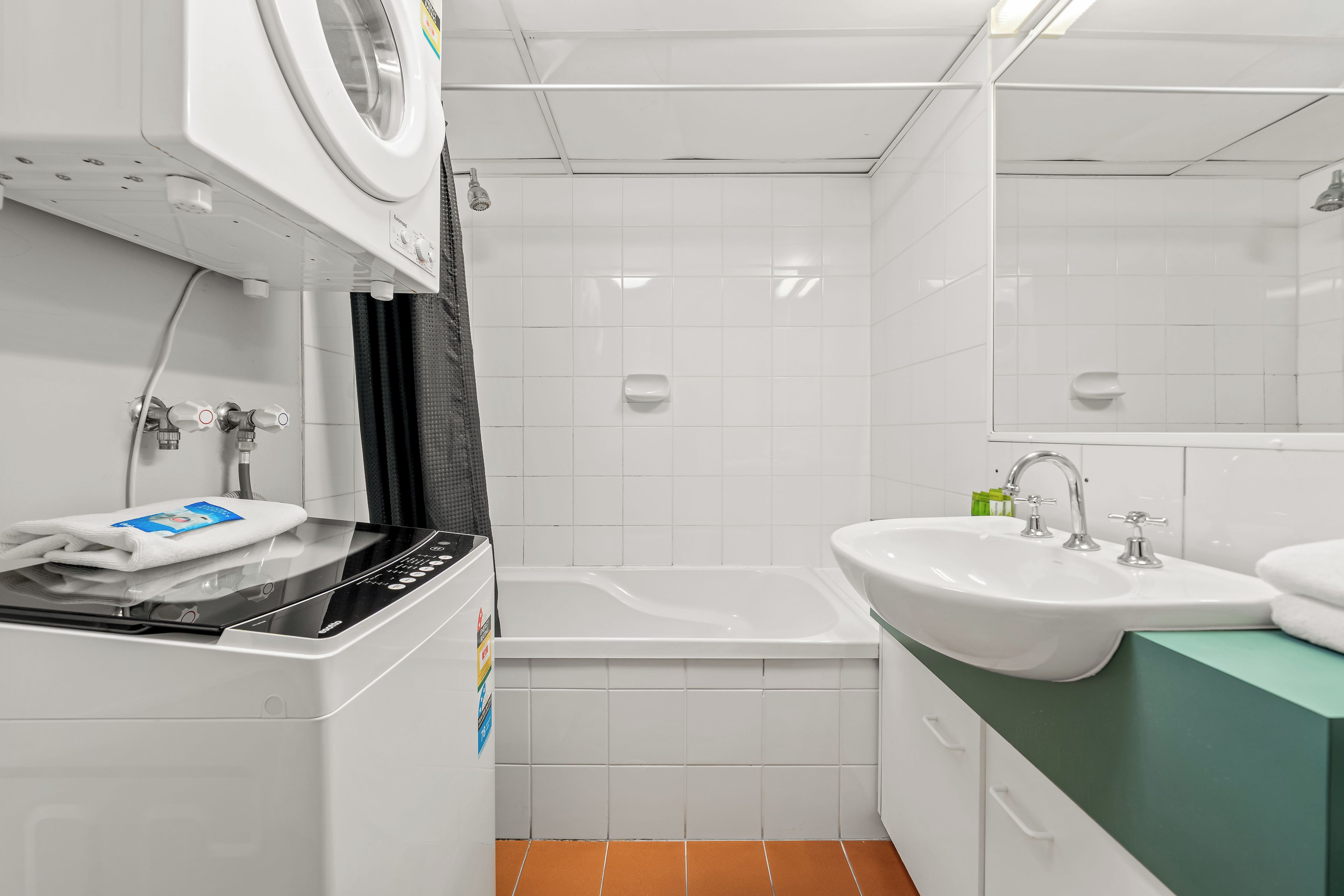 Ein kleines Badezimmer mit Waschmaschine, Badewanne und Waschbecken.