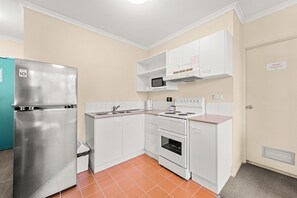 Una cocina compacta con un refrigerador de acero inoxidable, un microondas, una estufa y un lavaplatos.