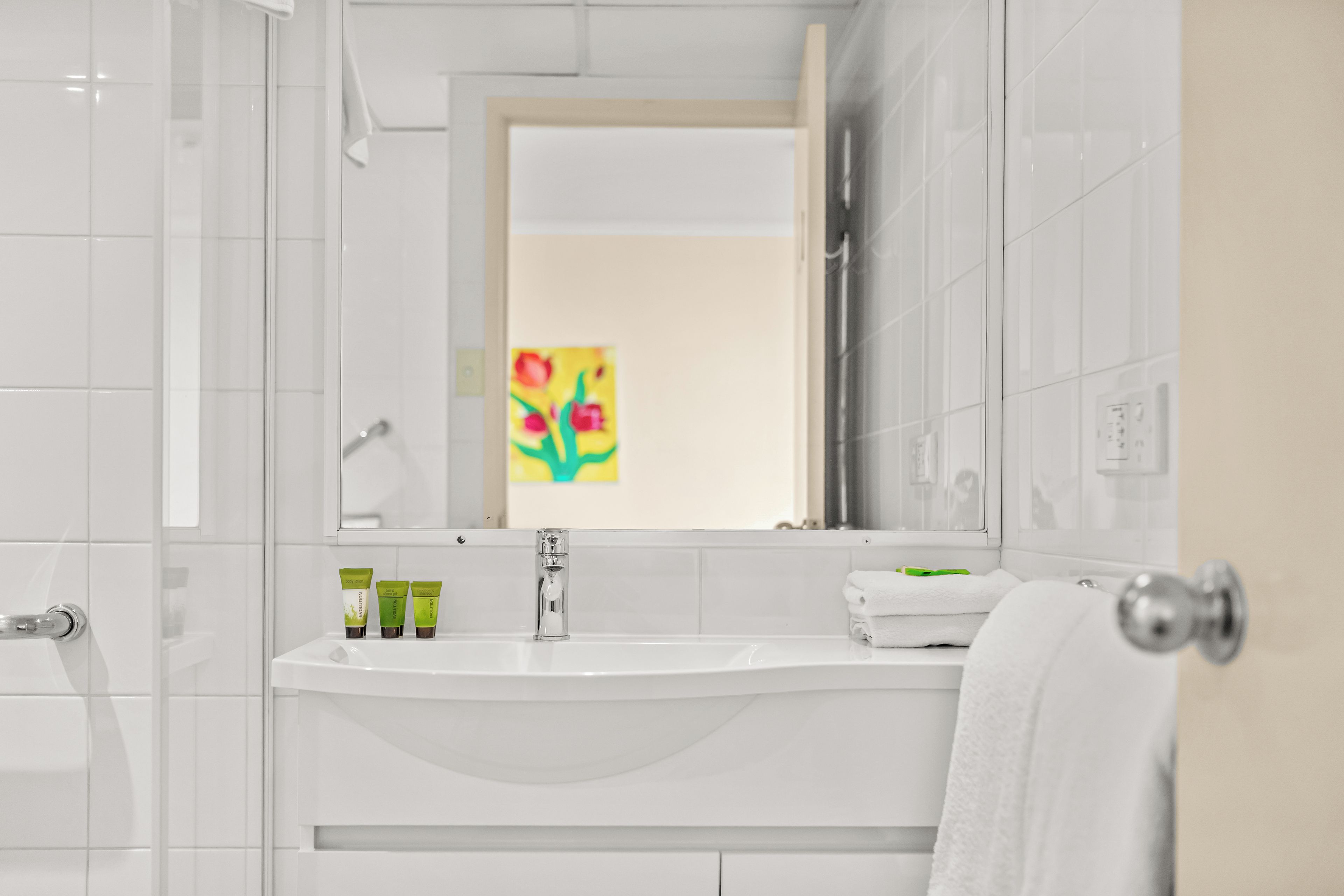 A bathroom with a white sink, a mirror, and a shower area.