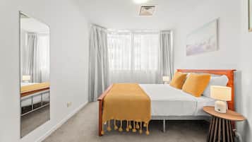Una habitación de hotel con cama, mesita de noche, lámpara y un cuadro en la pared.