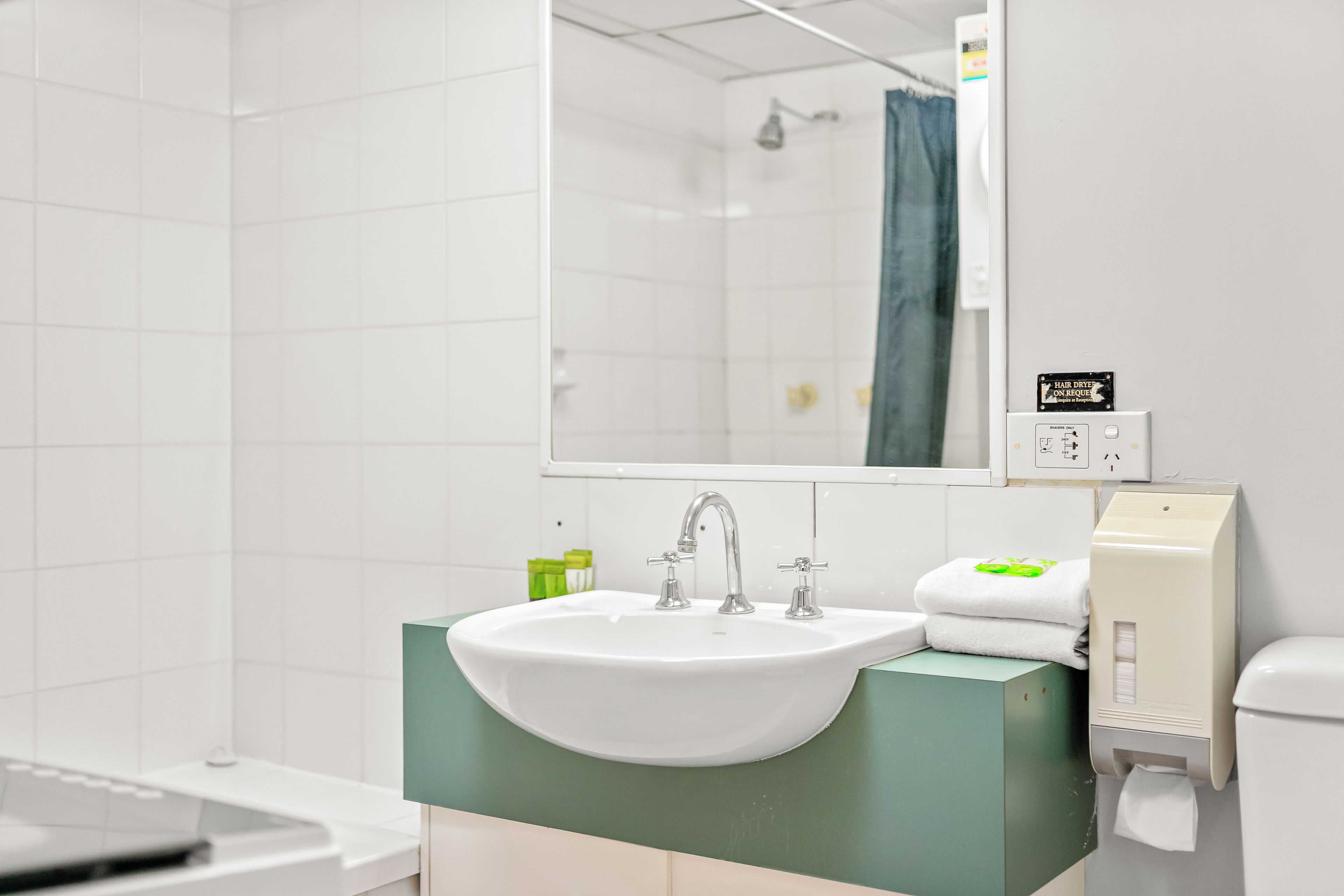 A bathroom with a white sink, green countertop, and a mirror above it.