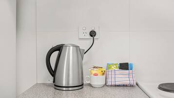 Une bouilloire posée sur un plan de travail, une tasse et un chiffon avec des produits de nettoyage.