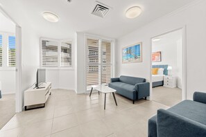 A modern living room with a sofa, a TV, and a white cabinet. - Chasely Apartment Hotel (Auchenflower)