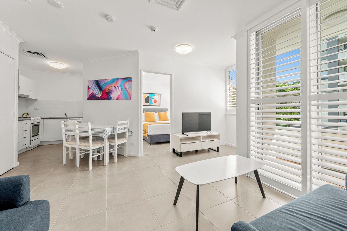 A modern living space with a dining area, kitchen, and a bedroom.