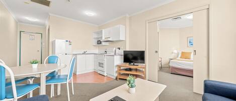Een hotelkamer met een kitchenette, een eethoek, een televisie en een bed.