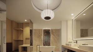 A modern bathroom with a freestanding bathtub, a large mirror, and a round bench. - Courtyard by Marriott Manado (Manado)