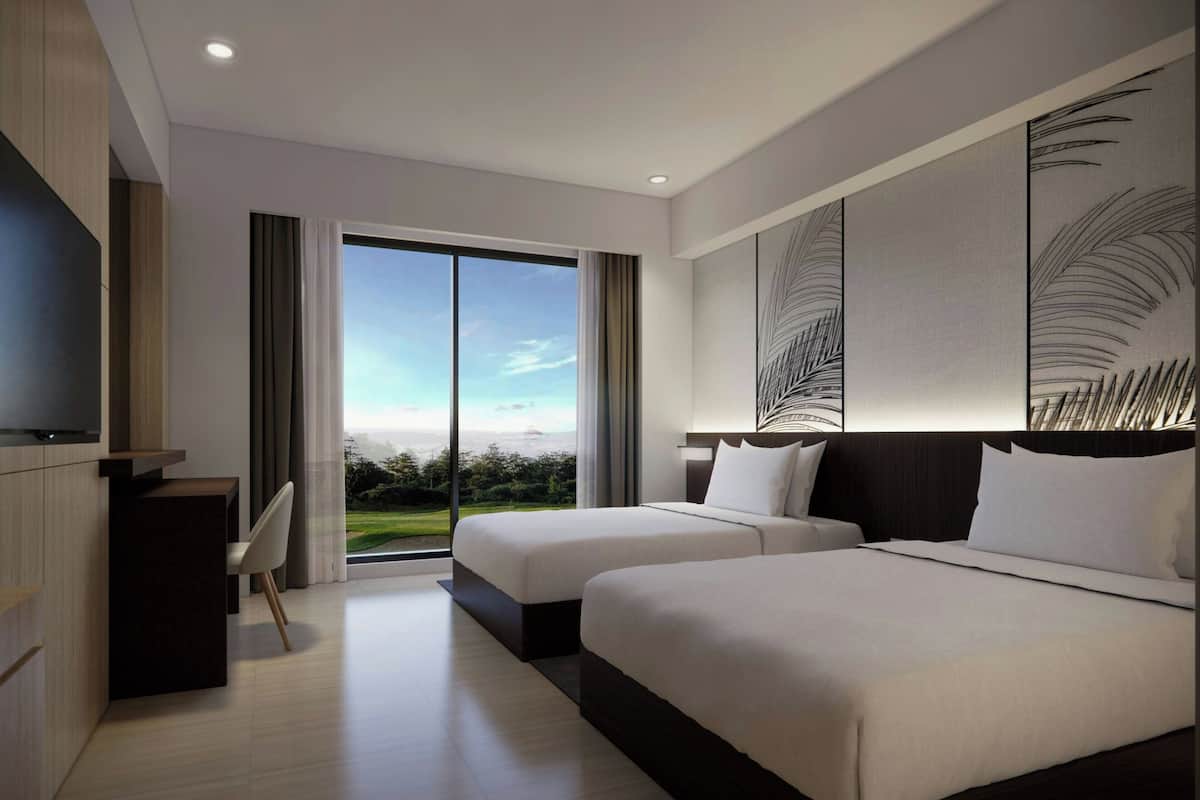 A modern hotel room with two beds, a desk, and a large window offering a view of the outdoors.