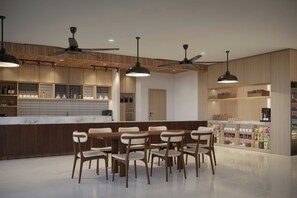 A modern kitchen with wooden cabinetry, a marble countertop, and a dining area with wooden chairs.