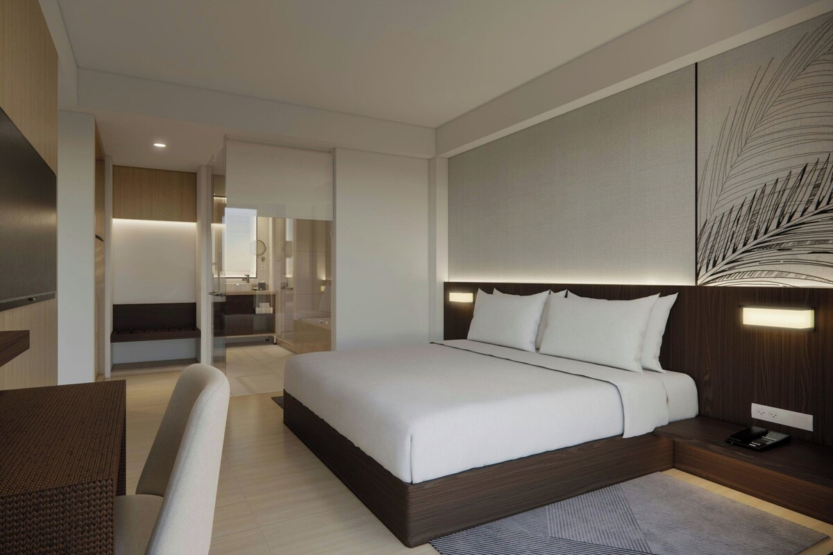 A modern hotel room with a large bed, a desk, and a chair.