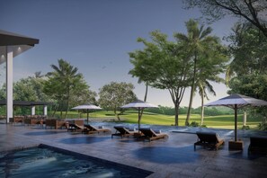Zona de piscina con sillas de descanso y sombrillas, rodeada de árboles y vistas a un campo de golf.