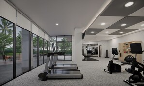 A modern gym with treadmills, exercise equipment, and large windows offering views of the outdoors. - Courtyard by Marriott Manado (Manado)