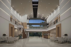 Un vestíbulo espacioso con techo alto, una escalera y vistas al exterior.