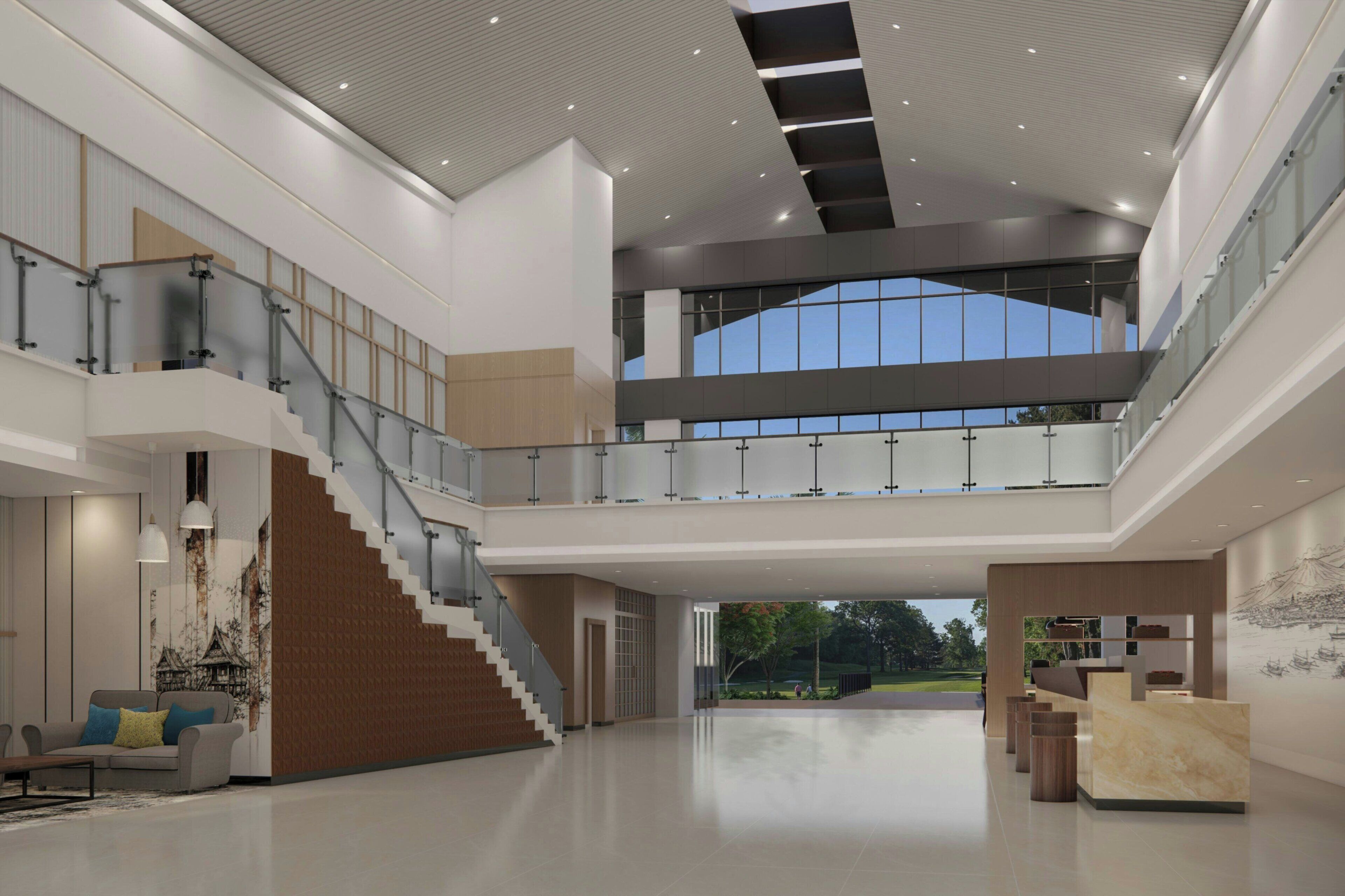 Un interior amplio con una escalera central, un mostrador de recepción y vistas al exterior.