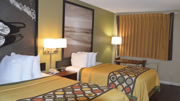 Habitación de hotel con dos camas, un escritorio y una silla. Hay dos lámparas a cada lado de la cama.