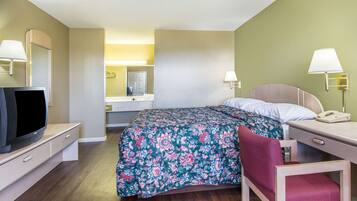 Una habitación de hotel con cama, escritorio, silla, televisor y teléfono.