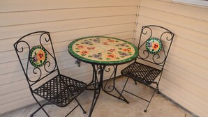 Un pequeño patio al aire libre con una mesa redonda y dos sillas.