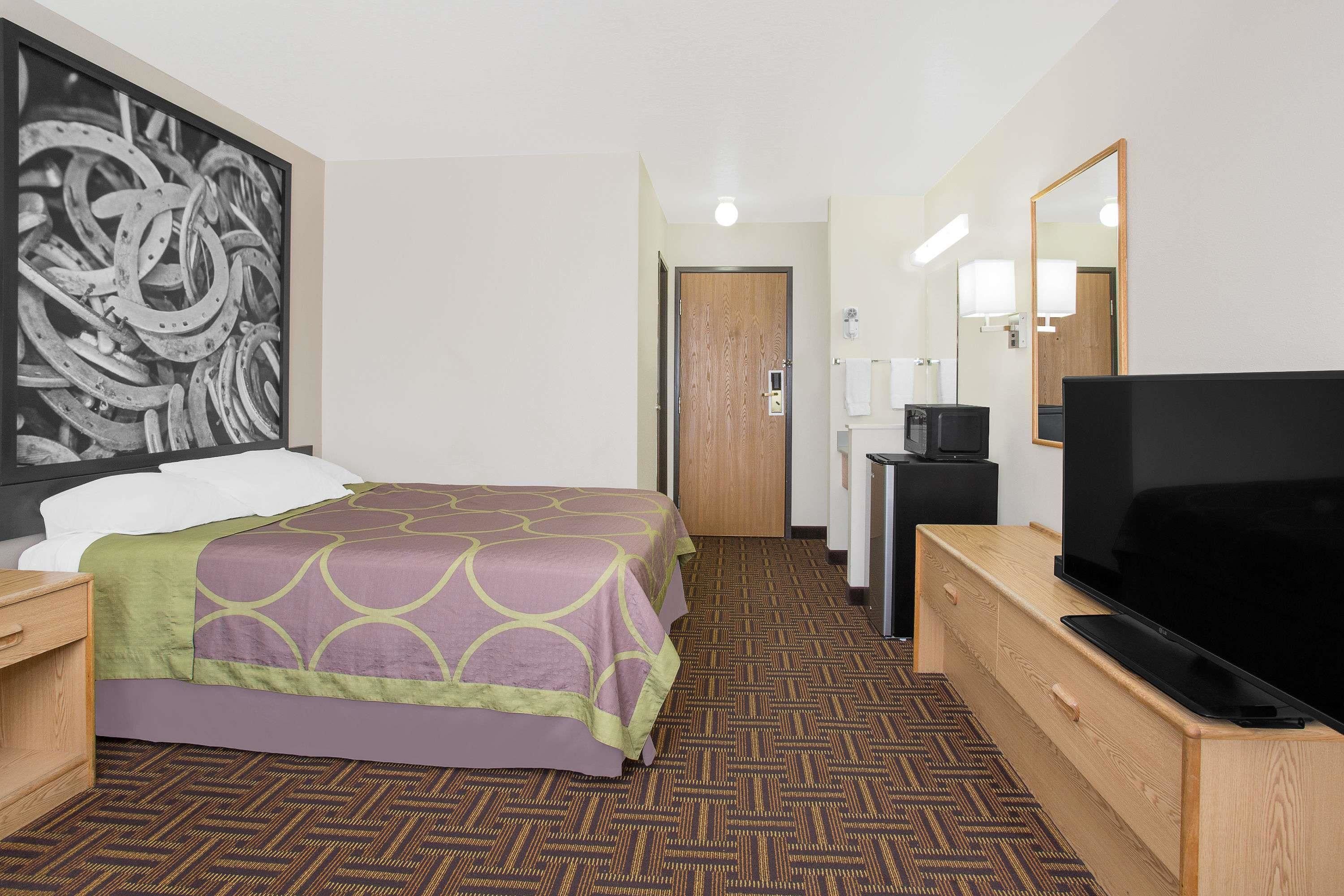 Ein Hotelzimmer mit Bett, Fernseher, Schreibtisch und einem großen Spiegel.