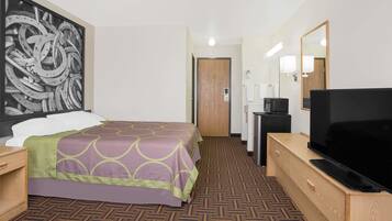 Ein Hotelzimmer mit Bett, Fernseher, Schreibtisch und einem großen Spiegel.