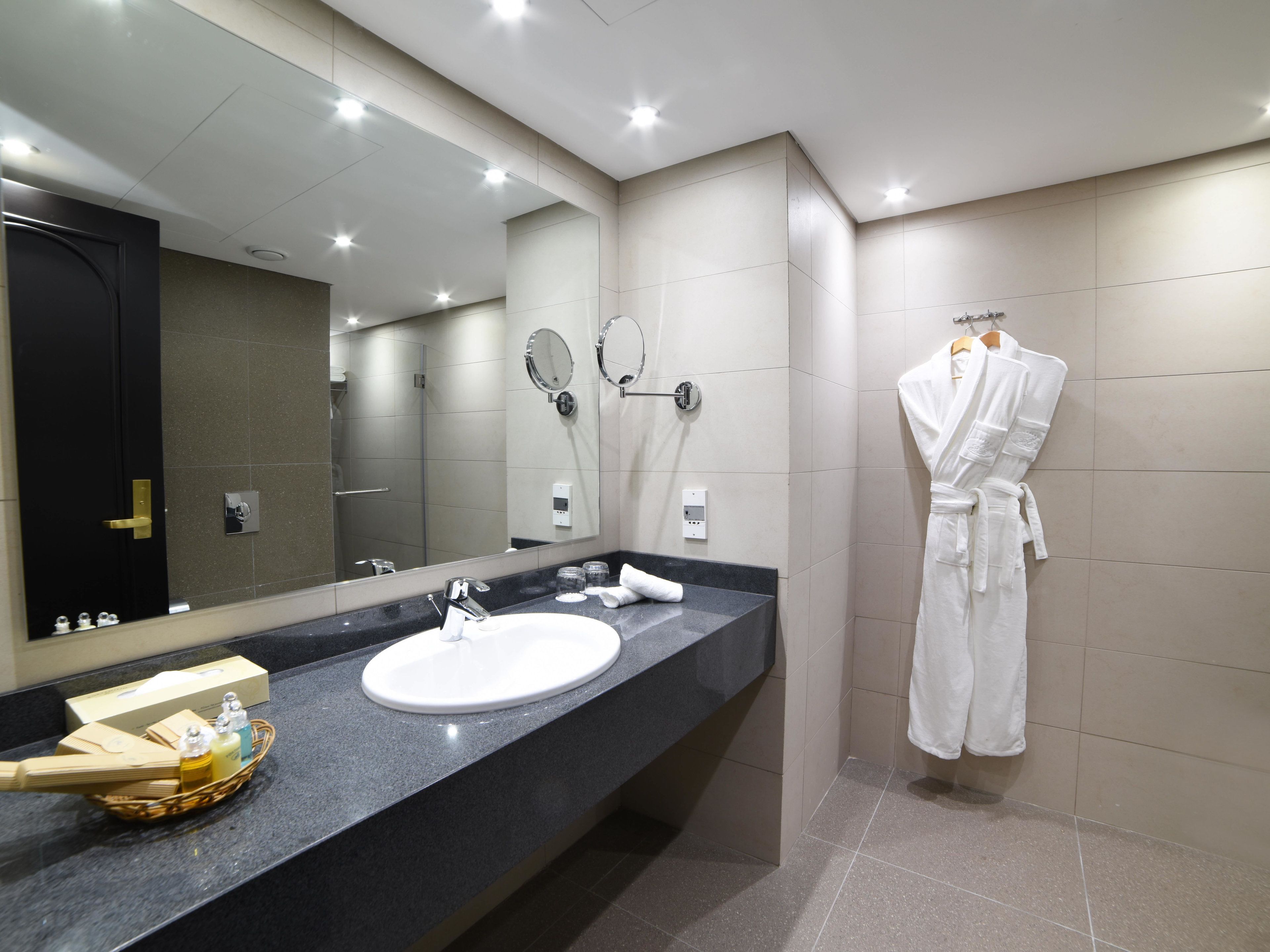 Un baño moderno con un espejo grande, un lavabo y un perchero para bata.