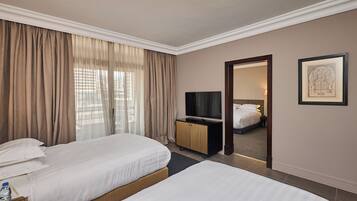 A hotel room with two beds, a TV, a minibar, and a framed picture on the wall.