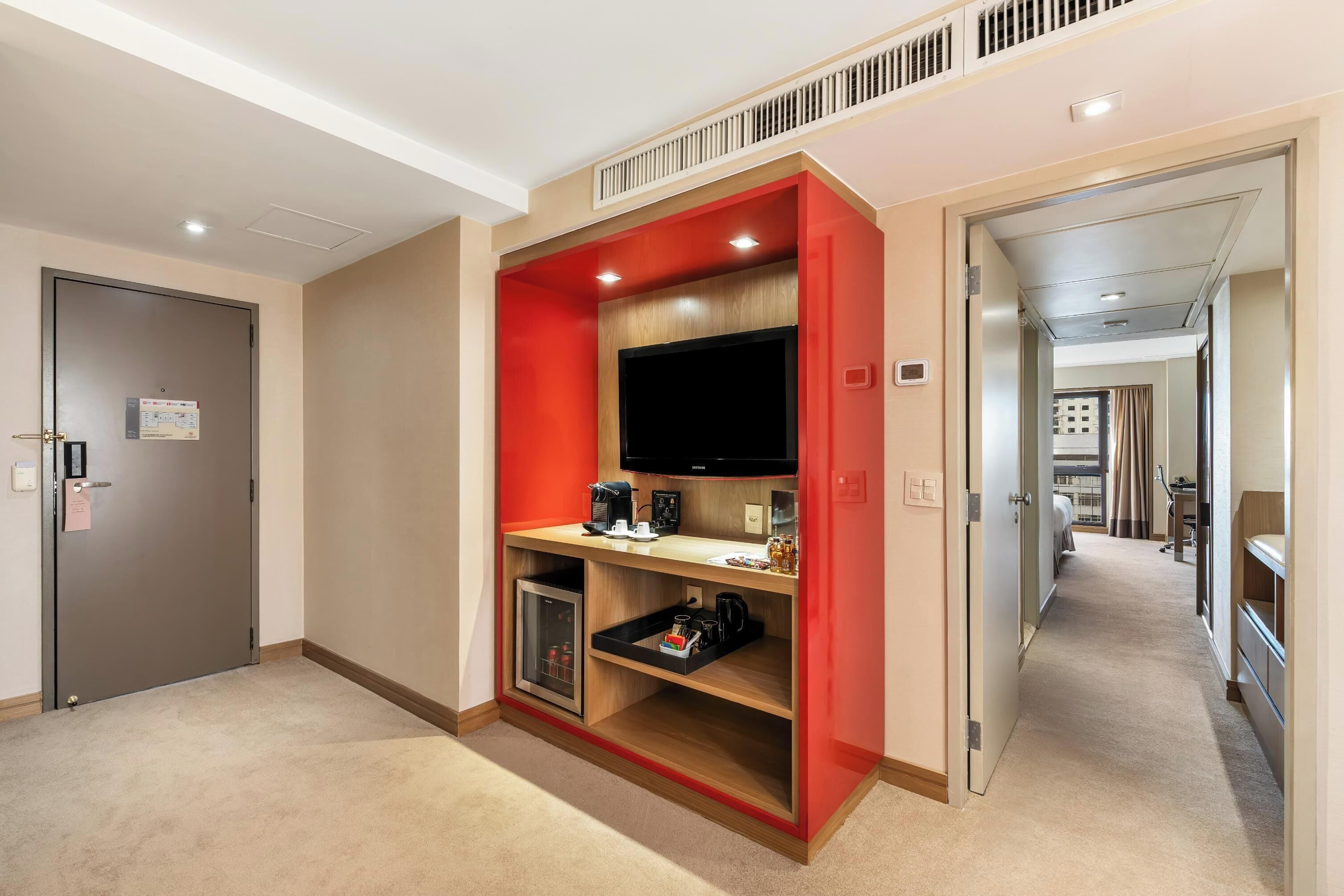 Une chambre d’hôtel équipée d’une kitchenette, d’un téléviseur à écran plat et d’une porte avec une pancarte.