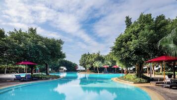 Una piscina al aire libre, sombrillas, sillones reclinables de piscina