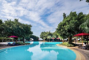 Una piscina al aire libre, sombrillas, sillones reclinables de piscina