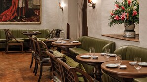 Un restaurante con asientos tapizados en verde, mesas de madera y una araña.