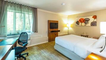 Una habitación de hotel con cama, escritorio, silla, televisor y una obra de arte en la pared.
