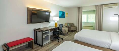 Une chambre d’hôtel avec deux lits, un bureau avec une chaise, une télévision et une fenêtre avec des rideaux.