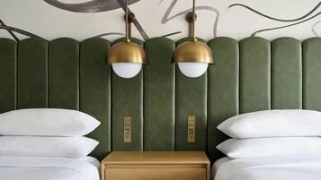A hotel room with a green upholstered headboard, two bedside tables, and two lamps.
