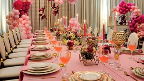 A banquet table set with pink and gold tableware, floral centerpieces, and pink balloons forming arches. - College Park Marriott Hotel & Conference Center (College Park)