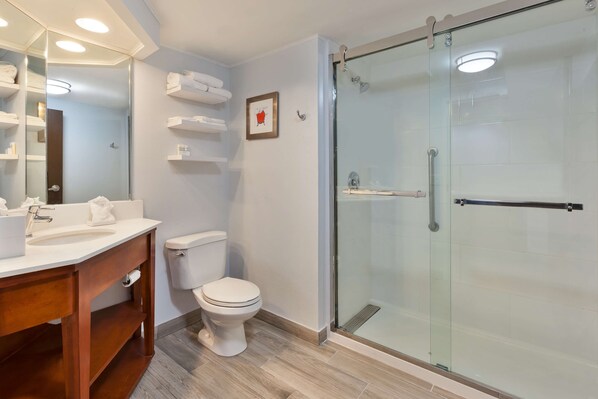 Une salle de bain moderne avec une douche à parois de verre, des toilettes blanches et un meuble-lavabo avec un miroir et un évier.