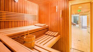 A sauna with wooden benches and a wooden bucket.