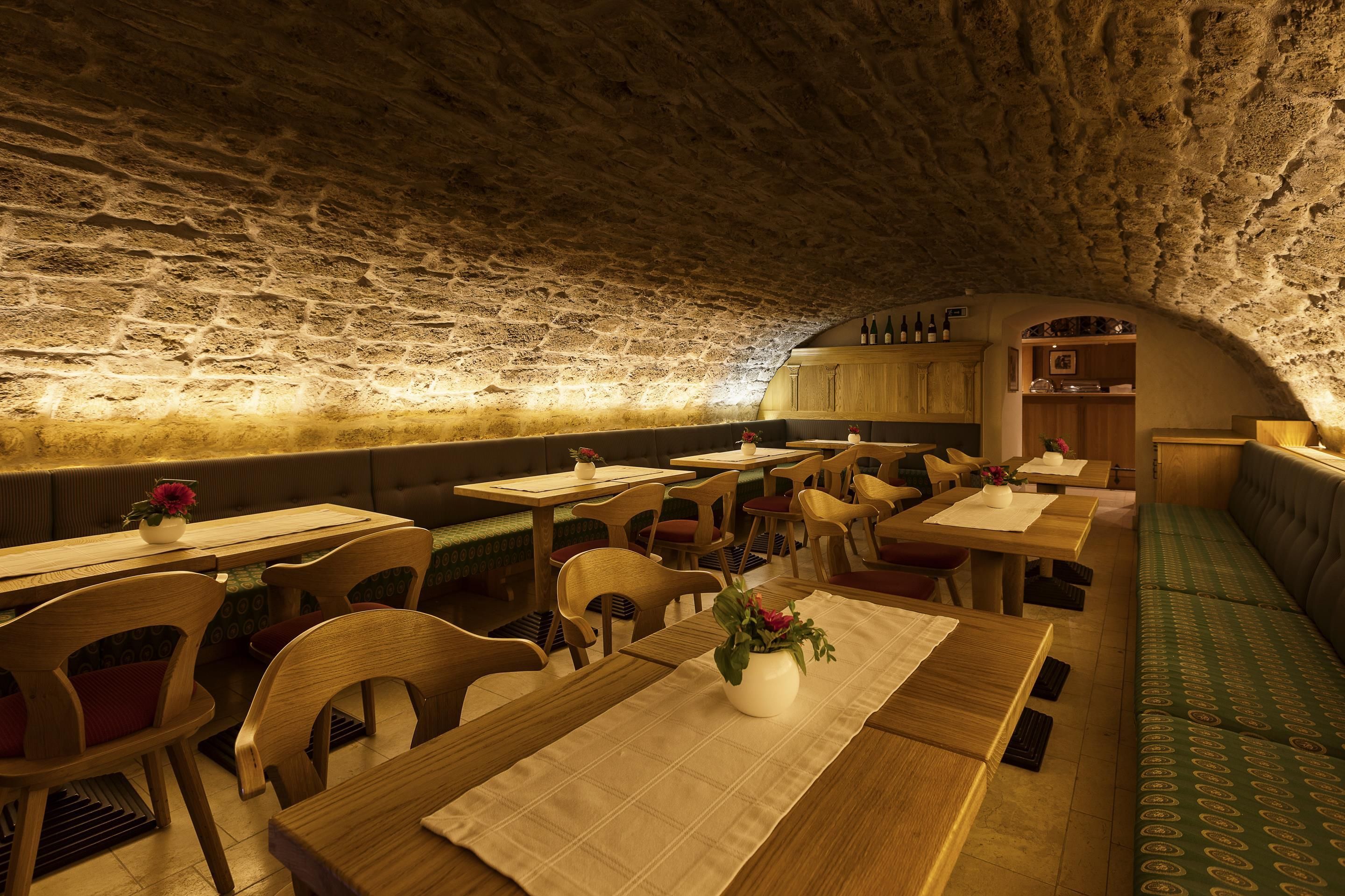 Un restaurant souterrain aux murs de pierre, aux tables et aux chaises en bois.
