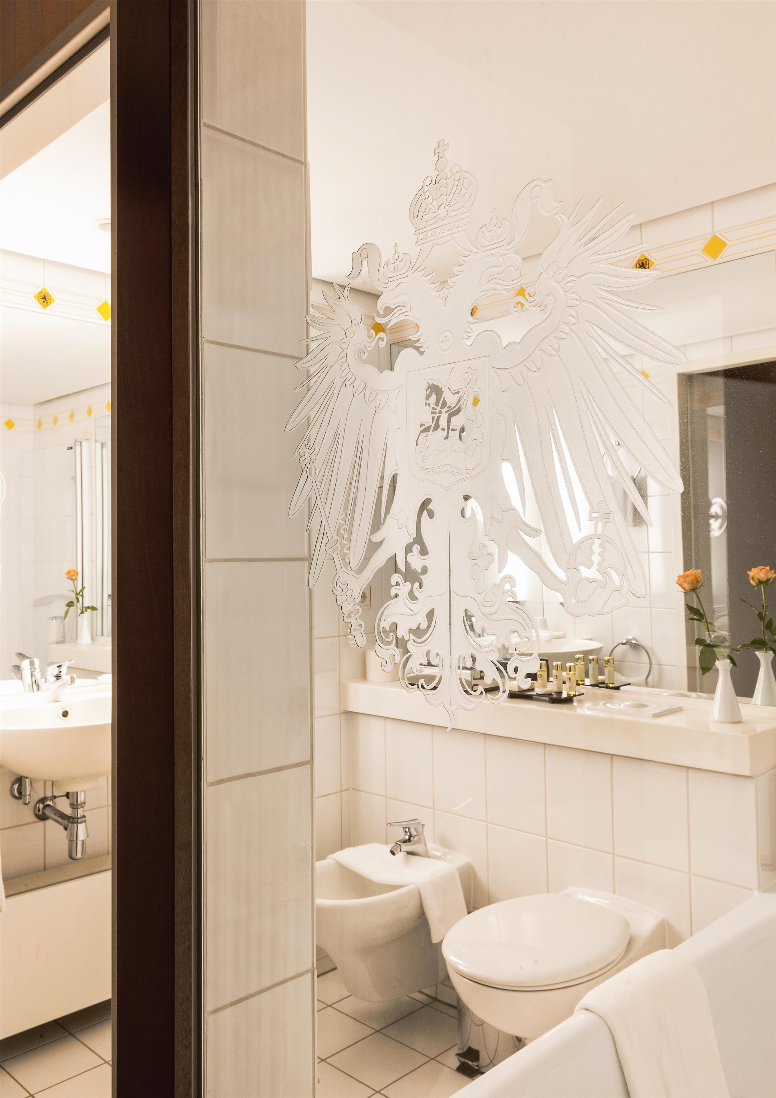 A modern bathroom with a large mirror, a sink, a toilet, and a bidet.