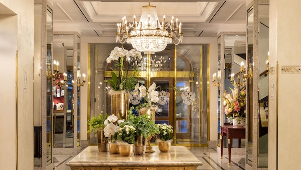 A grand lobby with a marble reception desk, a large chandelier, and potted plants. - Best Western Premier Grand Hotel Russischer Hof (Weimar)